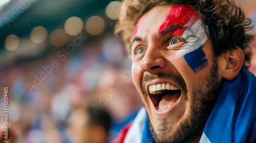 Ecstatic French soccer fan with facepaint cheering in stadium.	 photo