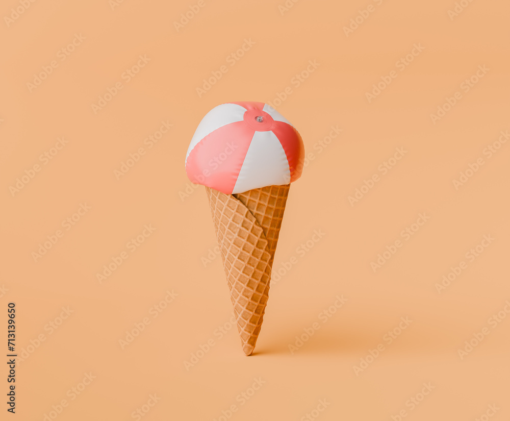 summer concept with a deflated beach ball like a scoop of ice cream atop a waffle cone on a peach-colored backdrop. summer concept with a deflated beach ball like a scoop of ice cream atop a waffle cone on a peach-colored backdrop.