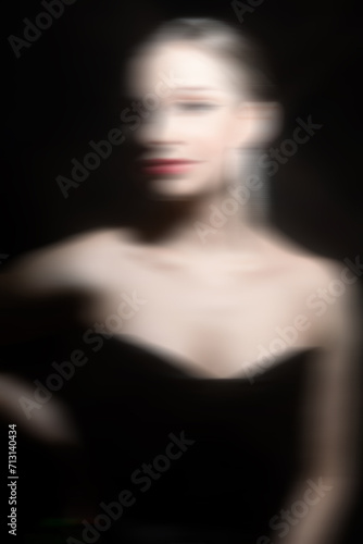 Make-up and fashion concept. Beautiful classic woman studio portrait. Model with classic hairstyle  fancy earrings  black dress and red lipstick. Model looking at camera. Motion blur effect style