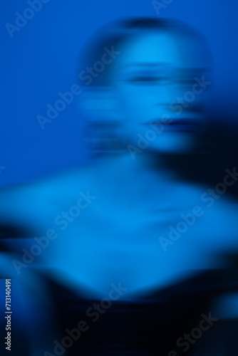 Beauty, fashion and make-up concept. Beautiful woman studio portrait with classic hairstyle, corset and round golden earrings. Toned image with vivid blue color. Motion blur effect style