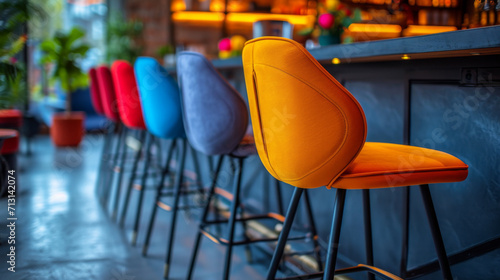 L'image montre une rangée de tabourets de bar modernes et colorés alignés le long d'un comptoir de bar. Un tabouret jaune est bien visible au premier plan, tandis que d'autres tabourets de couleur ble photo