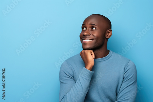 African American man thinking about his inspiration touch chin looking mockup choosing product option isolated on blue color background