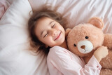 Top view of cute little preschooler girl lying cuddling with favorite fluffy toy waking up in cozy home bed