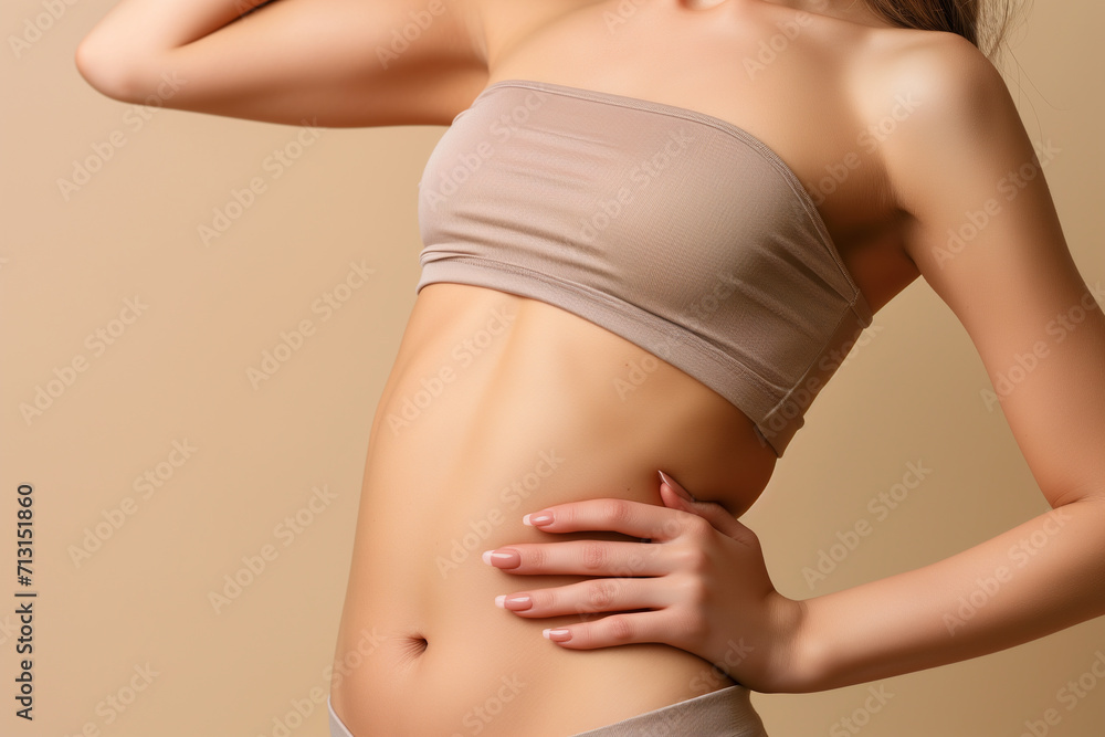 Young woman with flat belly on beige background, closeup. healthy life concept. Plastic surgery concept.