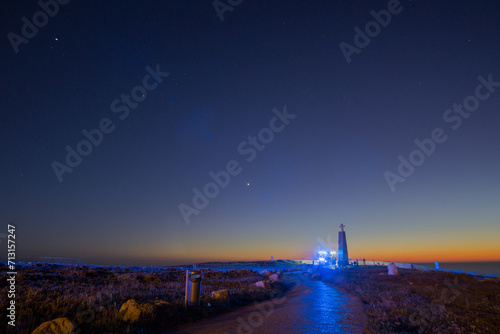 Path to the cross on a stone pillar at Cabo da Roca with fire truck with blue lights under the night sky, Sintra, Lisbon, Portugal photo