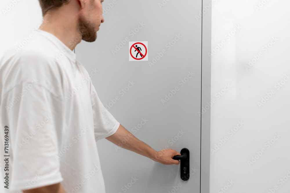 A person is seen opening a door with a clear no entry sign posted, potentially ignoring security protocol.