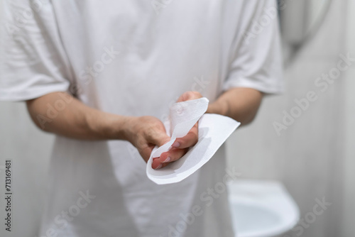 A person is captured drying their hands using a paper towel in the clean and well-lit confines of a modern bathroom setting. photo