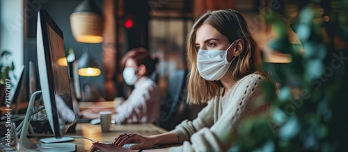 Young businesswoman and her colleague wearing face masks while working on a computer in the office during virus epidemic. Copy space image. Place for adding text