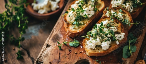 Home made bread on a wooden cutting board with curd cheese and ricotta and herbs Decorated with green herbs. Copy space image. Place for adding text