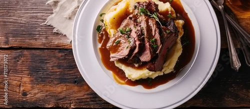 Valokuva Roast beef smothered in demi glace gravy with mashed potatoes on white plate Top view