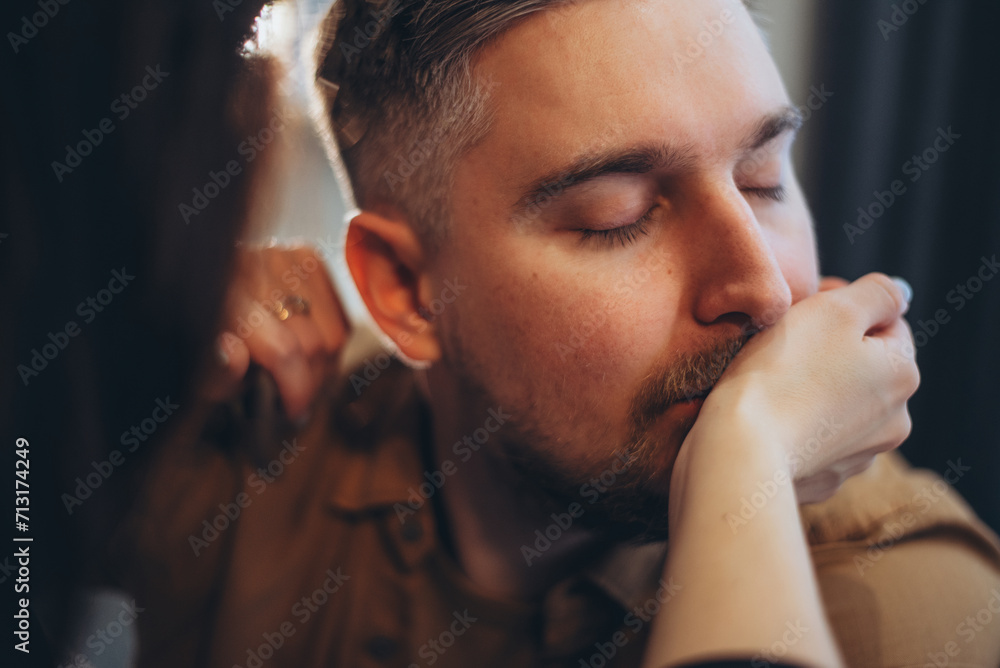 Close-up of the guy's face. The guy has a stylish beard and mustache. A guy with closed eyes kisses the hand of a girl who stands opposite him Close-up of the guy's face. The guy has a stylish beard and mustache. A guy with closed eyes kisses the hand of a girl who stands opposite him