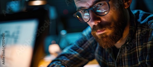 Closeup of young man in glasses with beard making blueprints on computer. Copy space image. Place for adding text