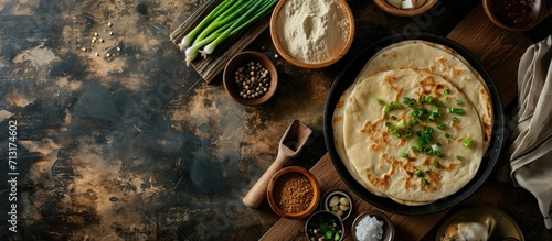 Chinese Scallion Pancakes in a skillet with uncooked pancake and ingredients on a wooden board view from above flatlay. Copy space image. Place for adding text photo
