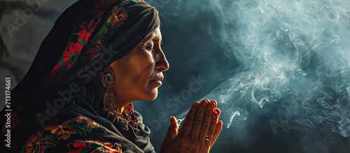 Mexican Latin woman with traditional clothes doing cleansing and spiritual meditations shaman with black shawl long hair pensive and concentrated among incense smoke together praying photo