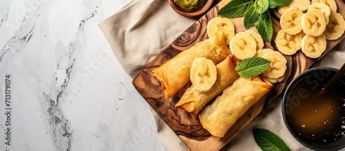 Delicious Banana rolls Indonesian snack made of fried banana wrapped in spring roll skin and assorted salted vanilla green tea toppings. Copy space image. Place for adding text photo