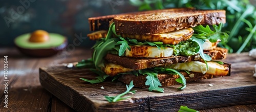 Grilled halloumi sandwich with avocado guacamole arugula Toast with grilled cheese and avocado Healthy food. Copy space image. Place for adding text photo