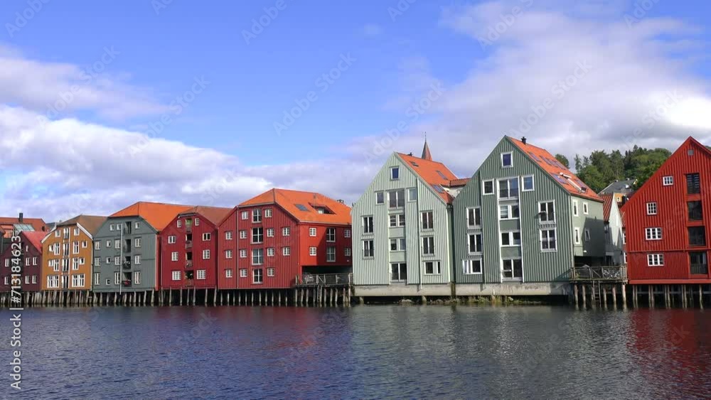 Trondheim, Norway-September 03, 2022: Beautiful bright and colorful houses on wooden stilts are built in a row in the water of the bay on a sunny day. Famous wooden colored houses in Trondheim city. Trondheim, Norway-September 03, 2022: Beautiful bright and colorful houses on wooden stilts are built in a row in the water of the bay on a sunny day. Famous wooden colored houses in Trondheim city.