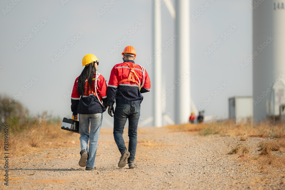Engineer and technician discussing on the road with wind turbines in the background