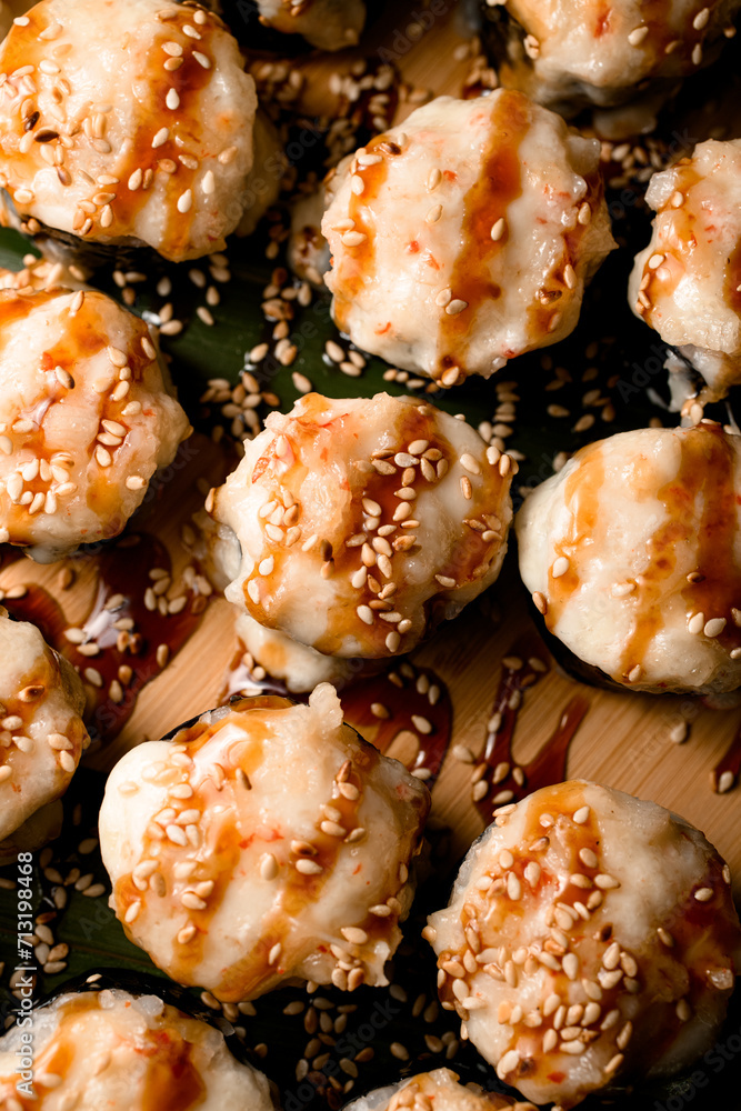 Focus on the foreground of baked sushi rolls with unagi sauce, sesame Focus on the foreground of baked sushi rolls with unagi sauce, sesame