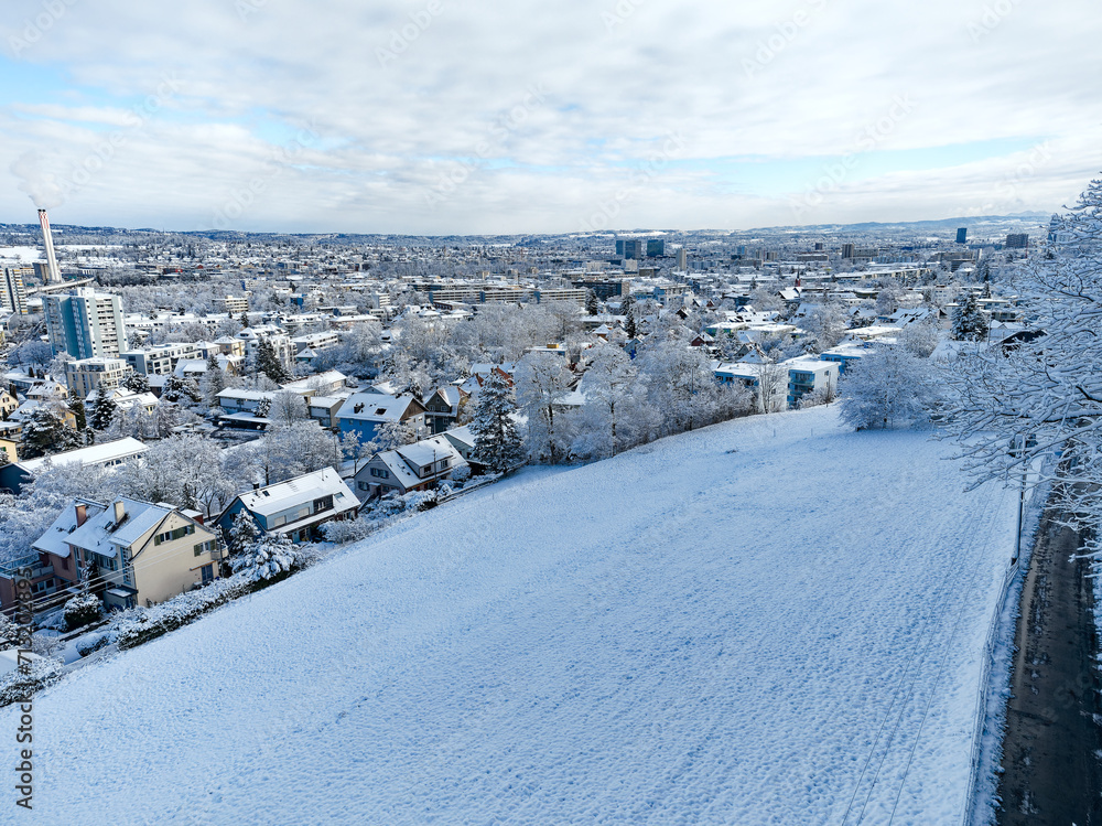 Aerial view of snow covered cityscape with meadow and rural road at Swiss City of Zürich on a snowy winter day. Photo taken January 19th, 2024, Zurich, Switzerland.