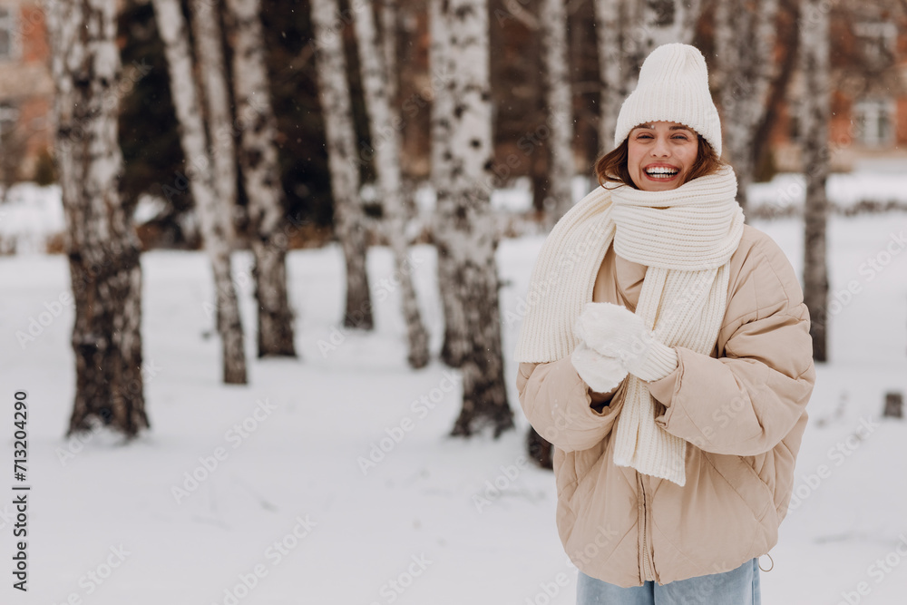 Happy smiling young woman portrait dressed coat scarf hat and mittens enjoys winter weather at birch winter park Happy smiling young woman portrait dressed coat scarf hat and mittens enjoys winter weather at birch winter park