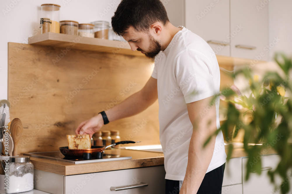 Handsome man preparing food at home. Young male surprise his beloved woman and making breakfast on kitchen Handsome man preparing food at home. Young male surprise his beloved woman and making breakfast on kitchen