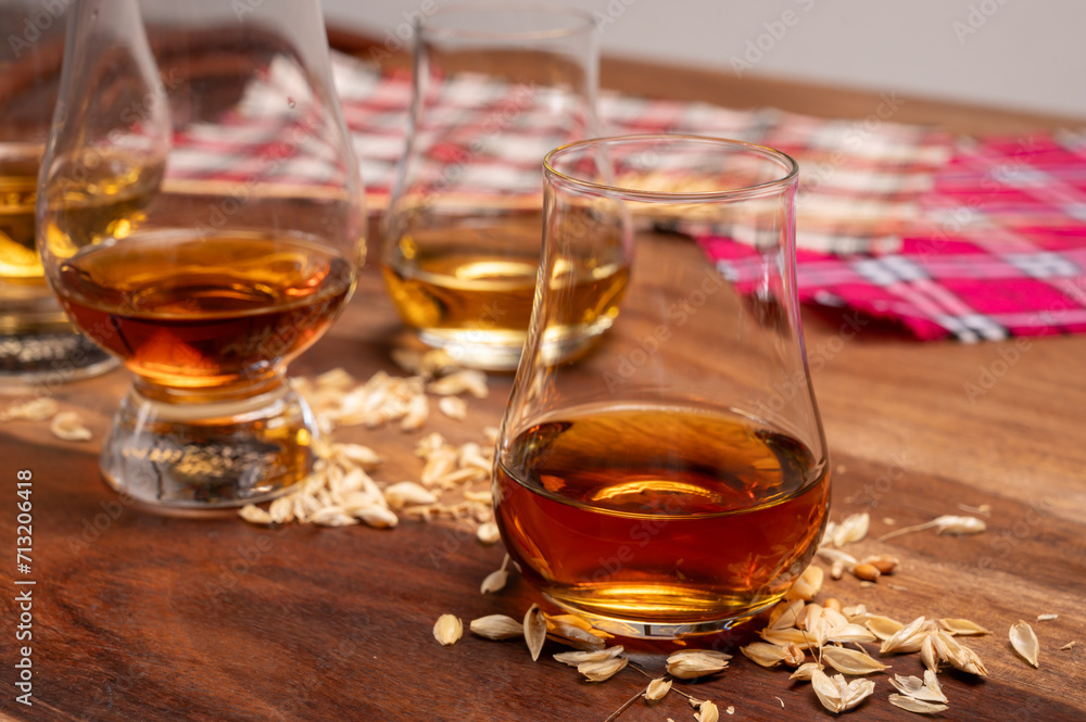 Tasting of different Scotch whiskies strong alcoholic drinks, drum of whiskey and colorful Scotch tartan on background close up Tasting of different Scotch whiskies strong alcoholic drinks, drum of whiskey and colorful Scotch tartan on background close up