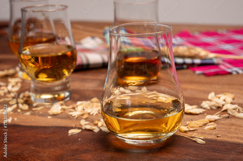 Tasting of different Scotch whiskies strong alcoholic drinks, drum of whiskey and colorful Scotch tartan on background close up Tasting of different Scotch whiskies strong alcoholic drinks, drum of whiskey and colorful Scotch tartan on background close up