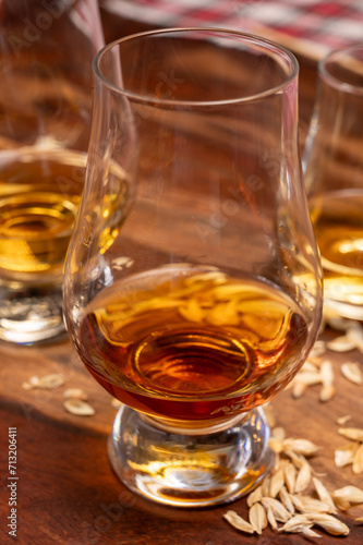 Tasting of different Scotch whiskies strong alcoholic drinks, drum of whiskey and colorful Scotch tartan on background close up