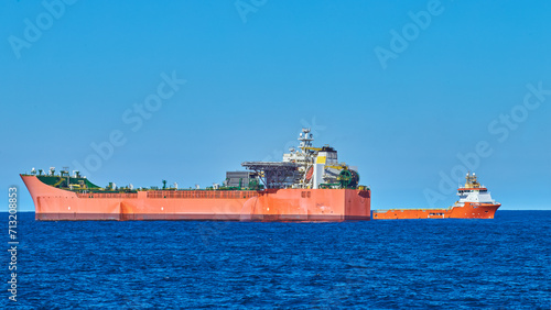 Cargo operations between Fpso tanker and supply vessel in the blue sea, on a calm sunny day with clear blue sky.