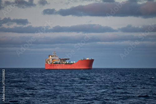 Picture of vessel in the blue sea on a sunny day with cloudy grey and blue sky.