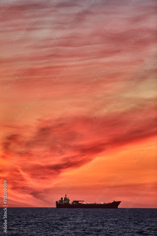 Colourful ocean sunset , with red and orange sky, dark sea and silhouette of a ship on the horizon. Colourful ocean sunset , with red and orange sky, dark sea and silhouette of a ship on the horizon.