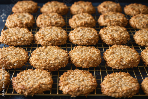 Freshly baked Anzac biscuits cooling on the rack, a golden blend of oats and coconut.