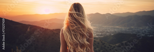 young woman in long red dress in the mountains at sunset