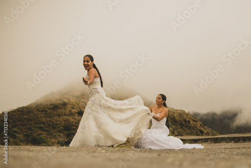 Retrato de una pareja de recién casados caminando al aire libre mientras llevan sus vestidos de novia y sonríen. photo