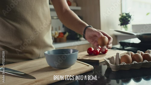Close up shot of hands of male chef cracking eggs into bowl while making breakfast, subtitles describing recipe step appearing belowClose up shot of hands of male chef cracking eggs into bowl while ma photo