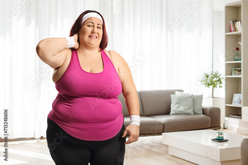 Woman in sportswear at home in a living room with a stiff neck