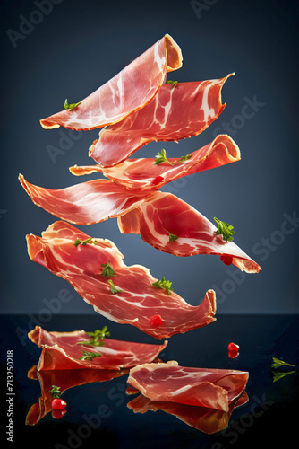 Slices of cured ham jamon Serrano Proscuitto, levitation floatinf food, black background.. photo