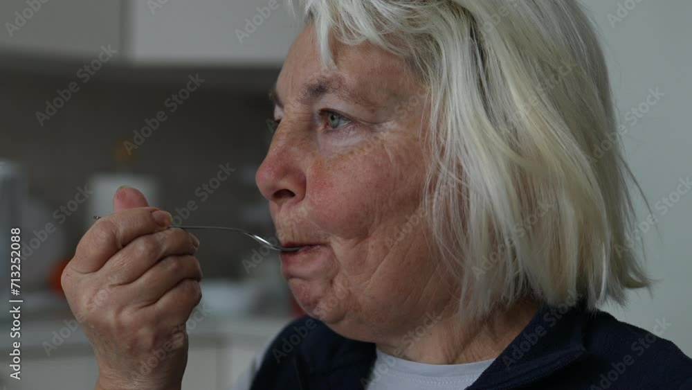 Happy senior 60s woman in a white T-shirt eating delicious tiramisu drinking a cup of coffee latte in an autumn morning at home. High quality FullHD footage Happy senior 60s woman in a white T-shirt eating delicious tiramisu drinking a cup of coffee latte in an autumn morning at home. High quality FullHD footage
