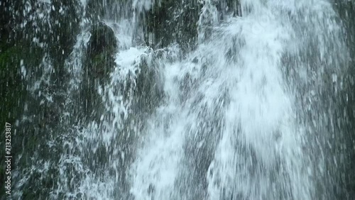 Water showering the ground in front of a waterfall (slow motion)