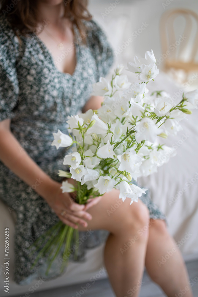 Girl holds a spring bouquet in her hands. Beautiful green dress in background.