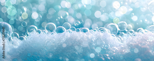 Frame with foam made of soap, shampoo, lotion, detergent on blue blurred backdrop. Macro photo of bubbles in water. Banner for laundry and cleaning services, spa, beauty and skin care concept.