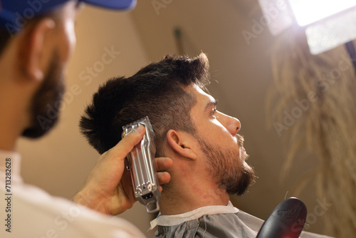 bearded and blonde man getting a cut in a barbershop
