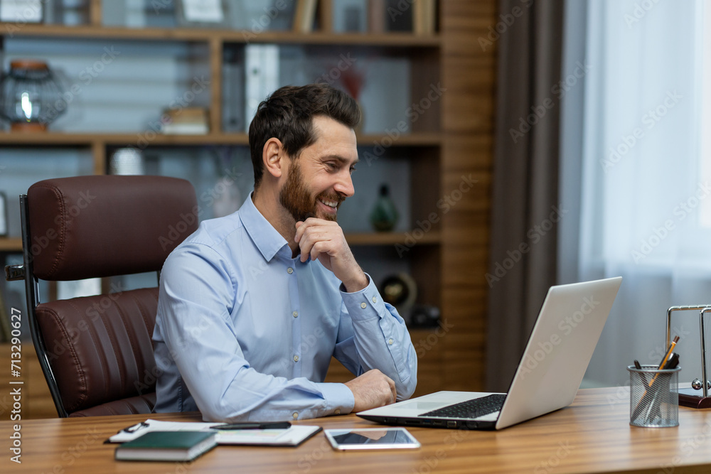 Smiling mature businessman at home office, engrossed in productive work on his laptop, exuding leadership and success. Smiling mature businessman at home office, engrossed in productive work on his laptop, exuding leadership and success.