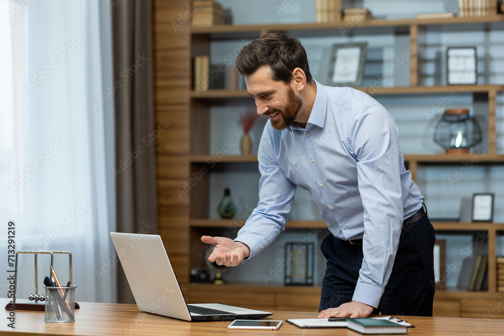Smiling mature male professional engaging in business activities from a well-organized home office with a laptop. Smiling mature male professional engaging in business activities from a well-organized home office with a laptop.