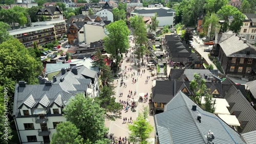 Zakopane main street underneath Tatra Mountains in Poland. Zakopane resort town. Green pine trees forest, cottages and hotels on hills. Aerial view picturesque mountain village. photo