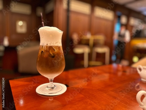 Iced cappuccino and milk foam with beautiful glass. Closeup and blurred background.