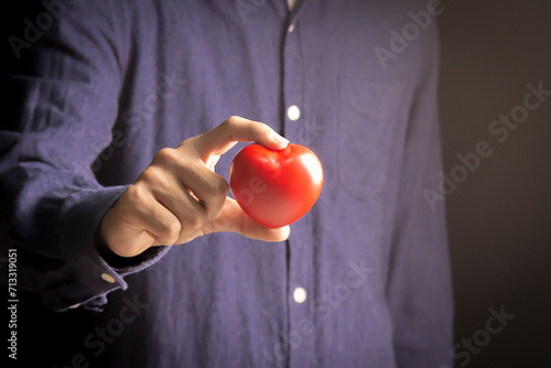 Close-up of a man's hand holding a red heart symbol,stock photography concept.