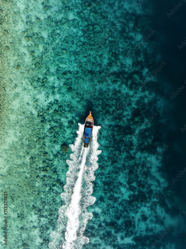 View from above, stunning aerial view of a longtail boat sailing on a turquoise water. Phuket, Thailand.