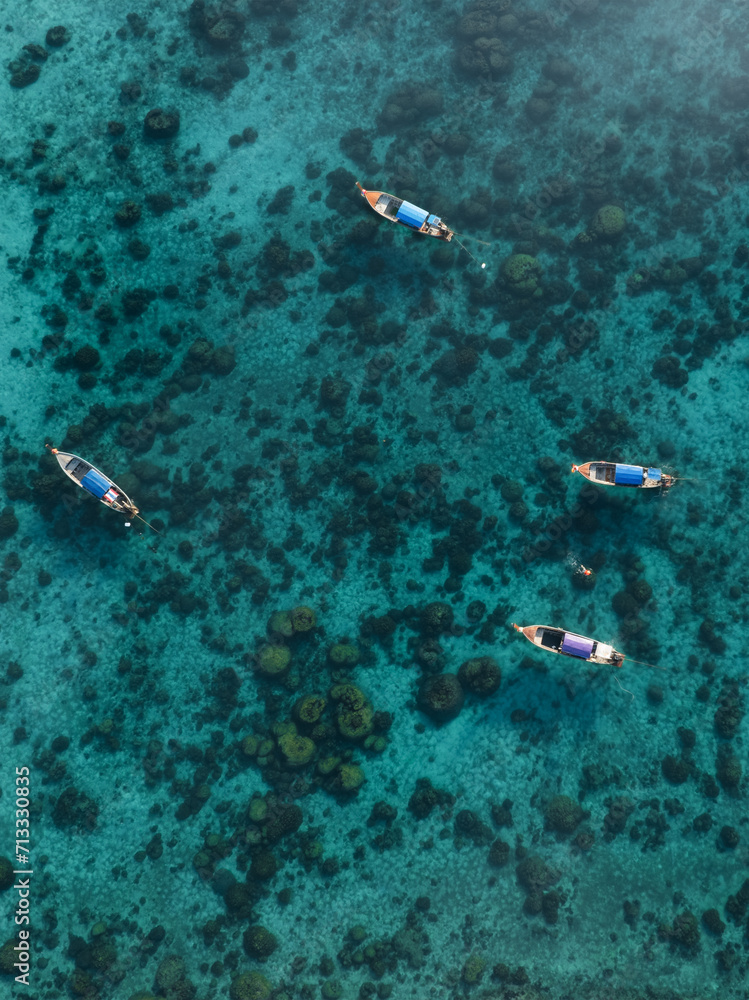 View from above, stunning aerial view of some long tail boats floating on a turquoise water. Phuket, Thailand.